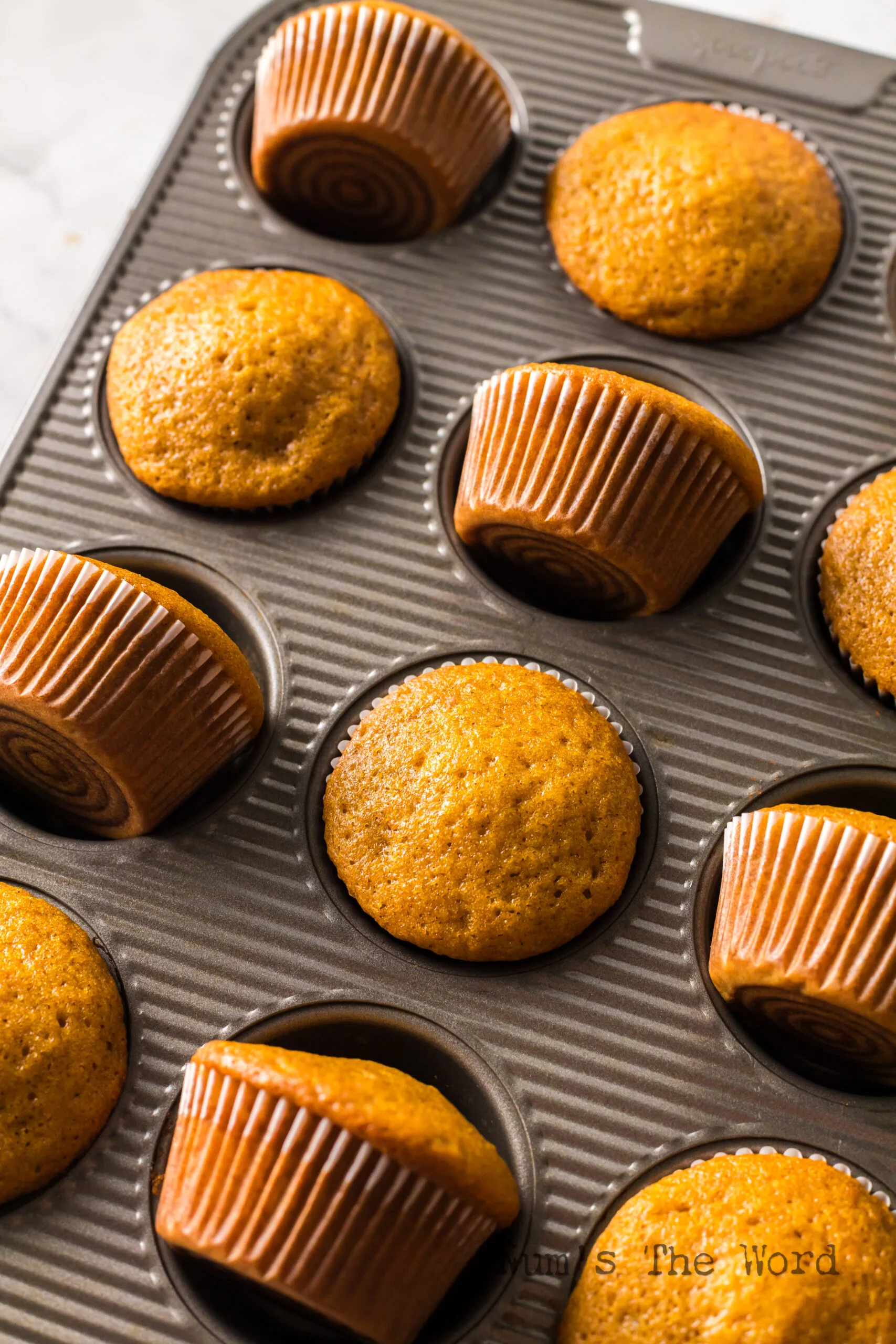 zoomed in image of muffins in pan with half the muffins tipped.