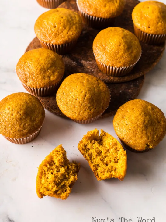 top view looking down at muffins on the counter. One muffin cut in half to show how yummy they are.