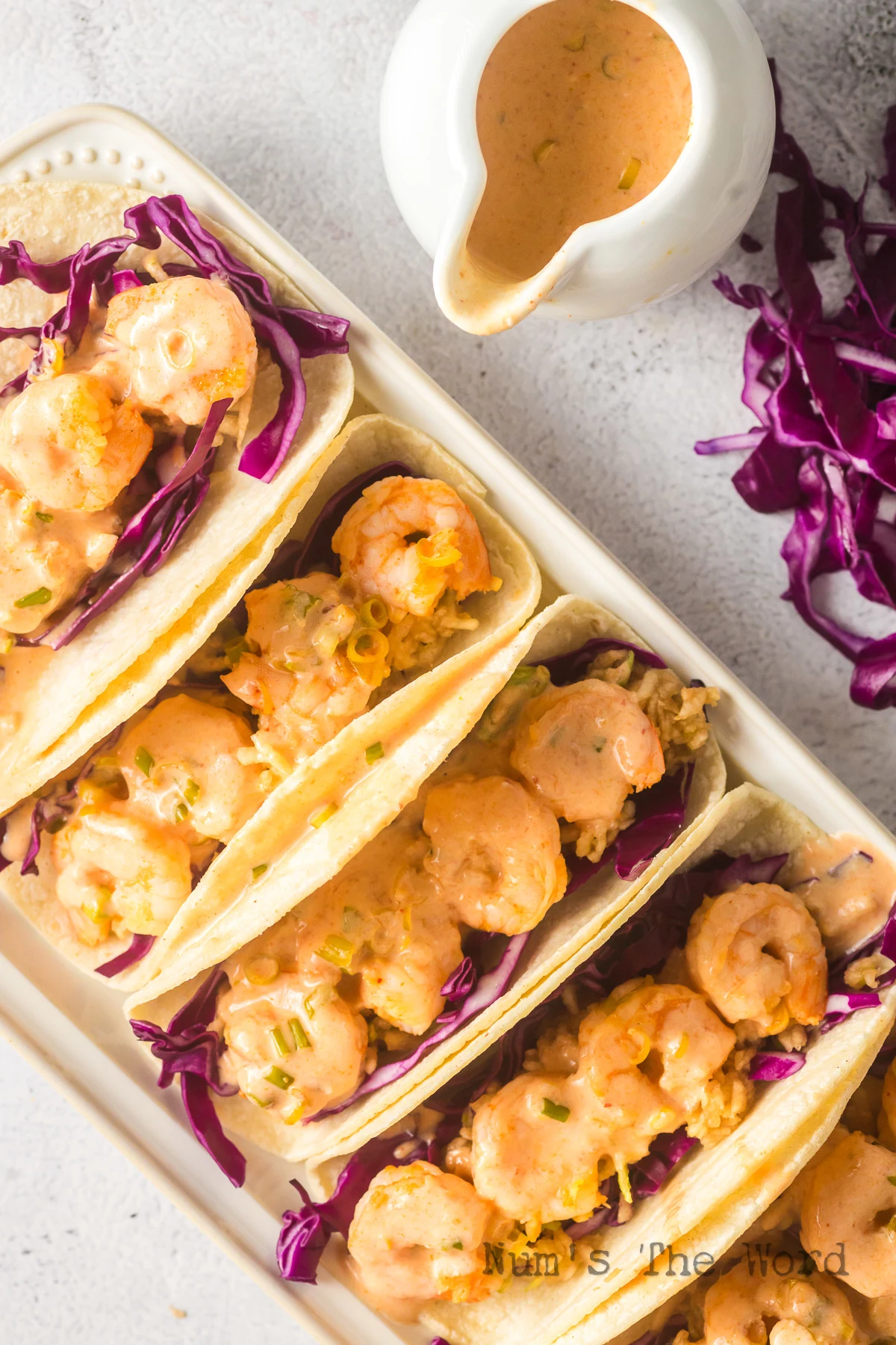 5 prepared tacos with sauce drizzled over the top.