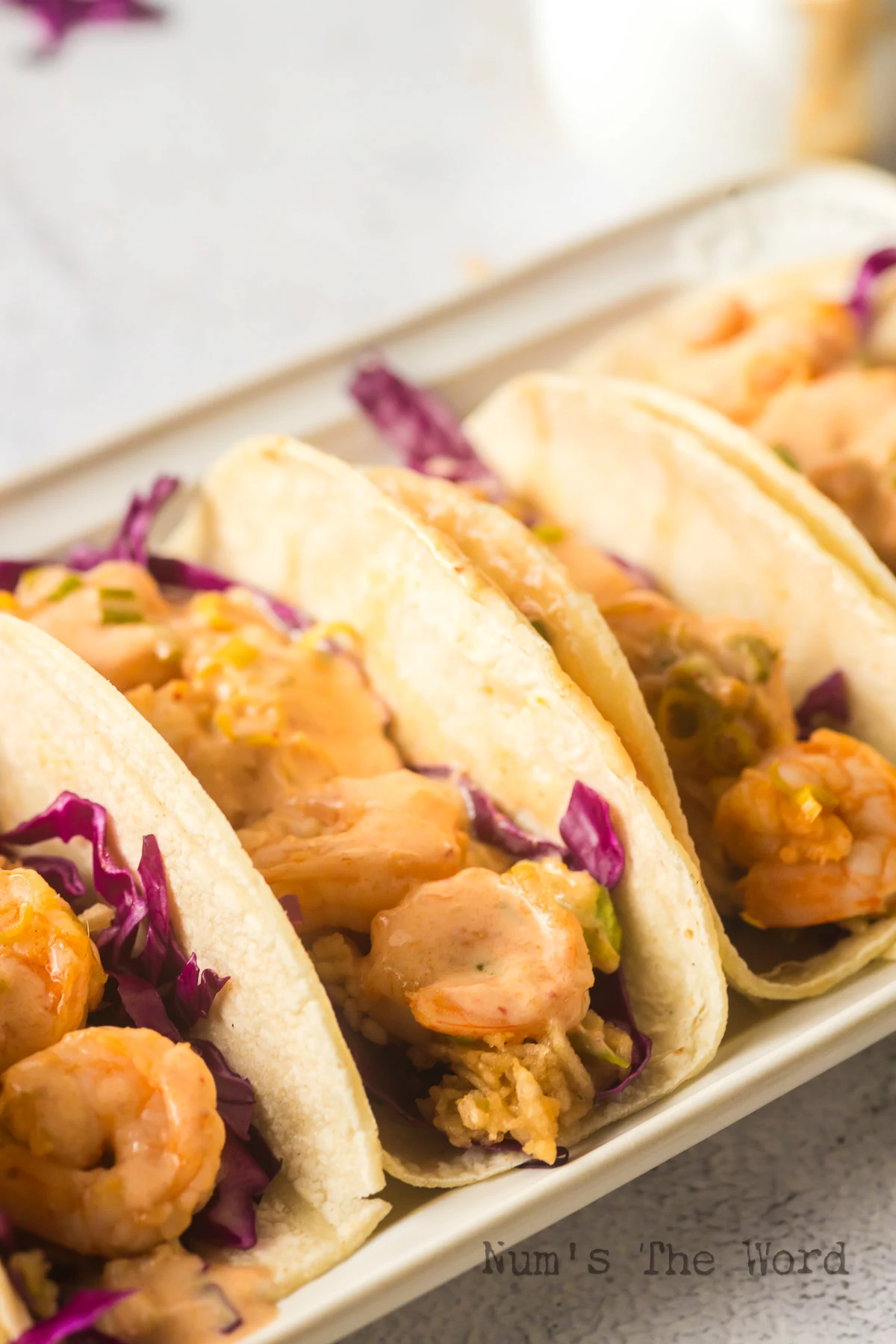 side view of shrimp tacos lined up and ready to eat.