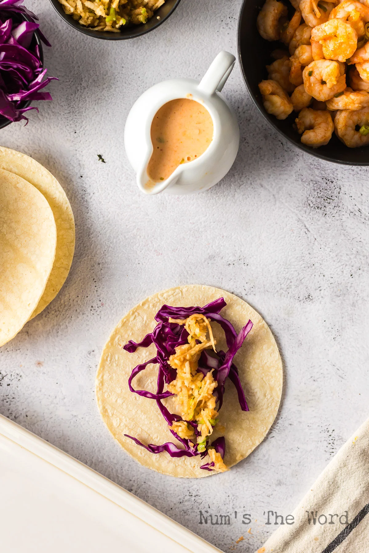 tortilla laid out on the counter with cabbage and apple slaw placed on top.