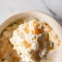 top view looking down at fruit salad with a wooden spoon scooping some out of the bowl.