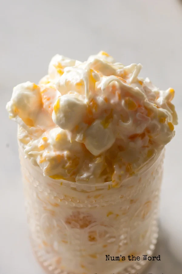 side view of fruit salad piled high in a serving jar.