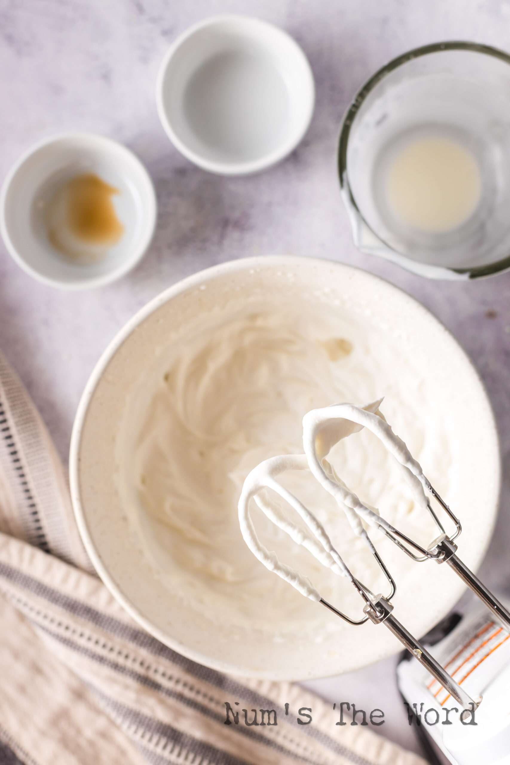 beaters standing above bowl, whipped cream at soft peak