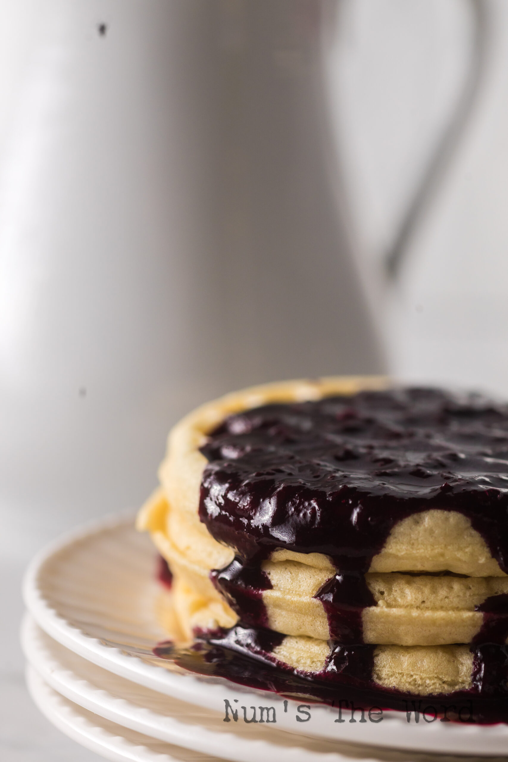 3 waffles stacked up with syrup on top.