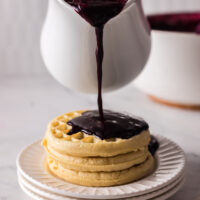 Syrup being poured onto waffles.