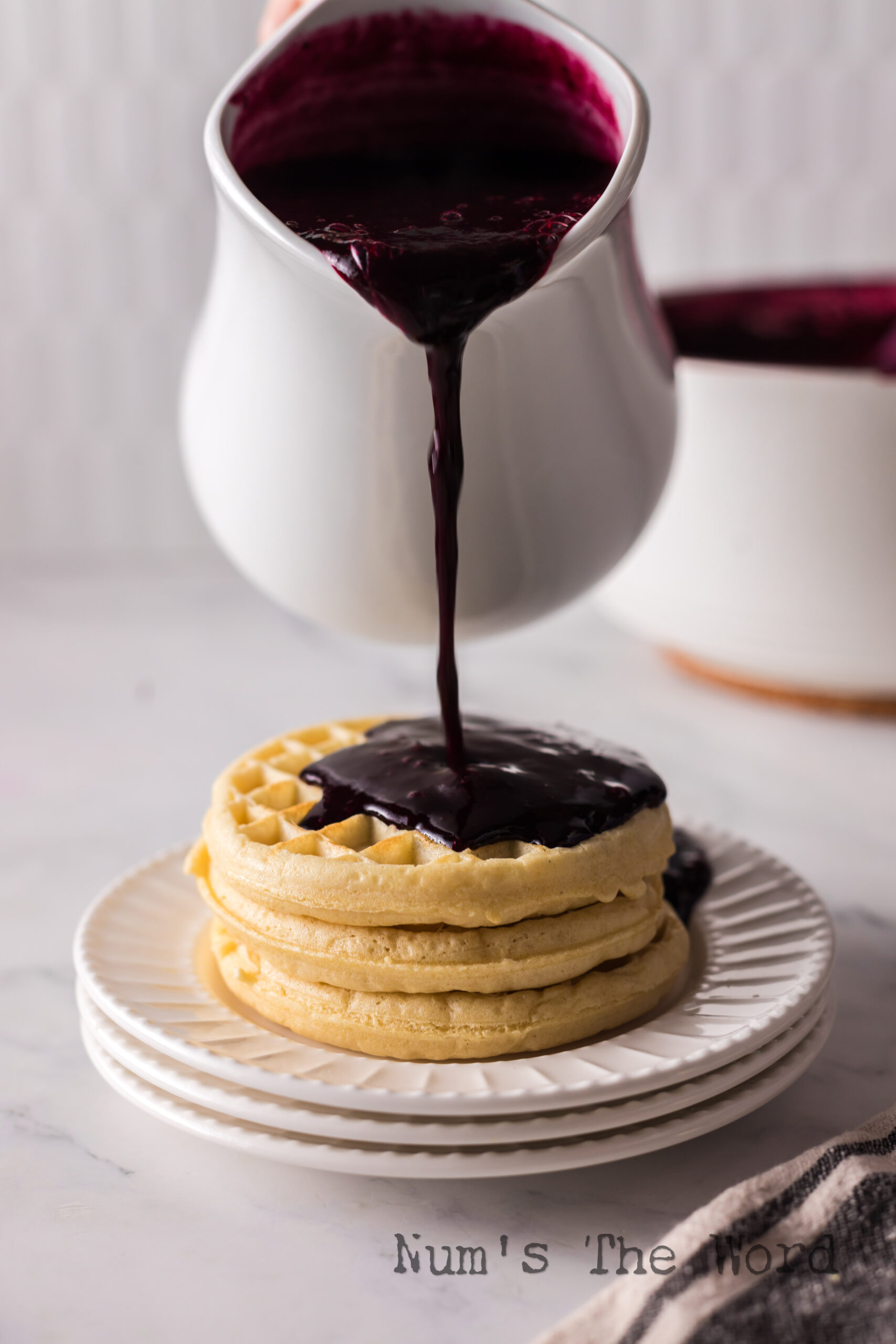 Syrup being poured onto waffles.