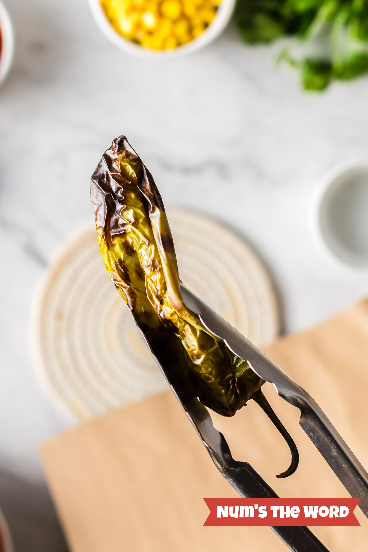 Roasted Poblano Pepper held in tongs.
